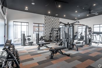 A gym with a variety of equipment including treadmills, weights, and exercise machines.